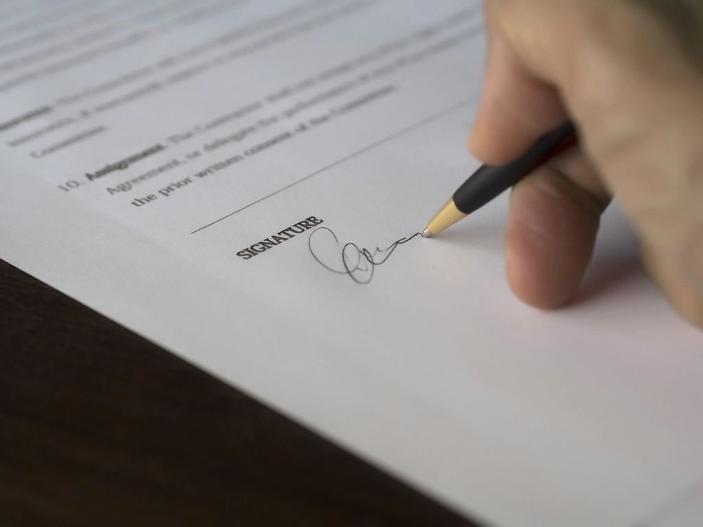 Hand signing a contract with a pen
